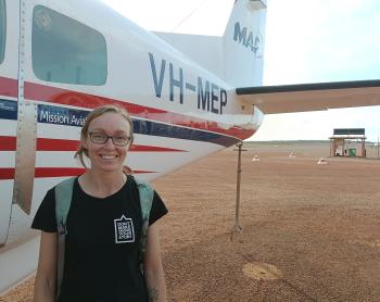 Public health worker standing in front of aircraft on Tarmac