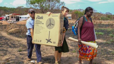 MAF pilot and teachers carry school equipment.
