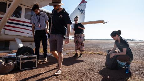 Pilot and healthcare workers with plane on apron.