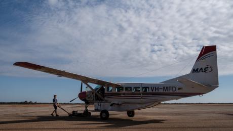 Maintenance engineer wheeling aircraft out of hangar.