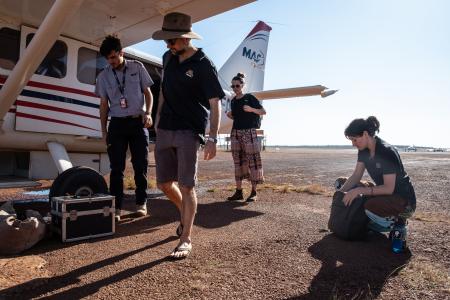 Pilot and healthcare workers with plane on apron.