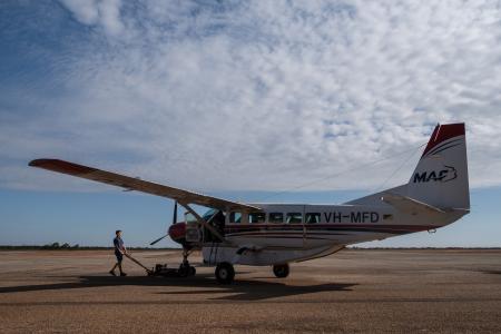 Maintenance engineer wheeling aircraft out of hangar.
