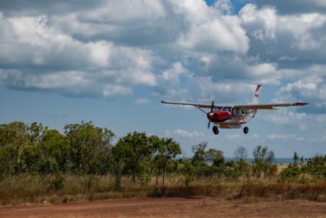 Plane coming in to land on dirt airstrip