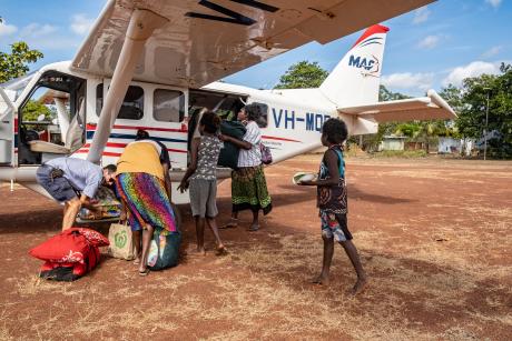 Homeland children greet student teachers at plane pilot unloads luggage